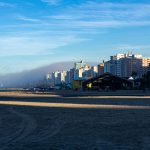 Orla da Praia Grande ao amanhecer, com edifícios altos à beira-mar.