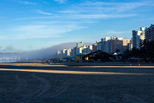 Orla da Praia Grande ao amanhecer, com edifícios altos à beira-mar.