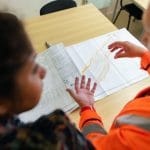 Duas pessoas analisam plantas de construção sobre uma mesa em um ambiente de trabalho.