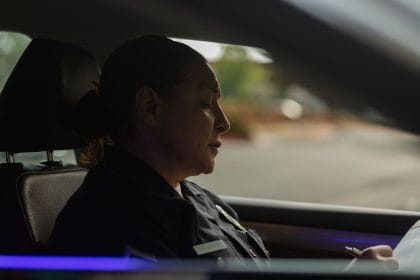 Policial uniformizada faz anotações dentro de uma viatura durante o serviço.