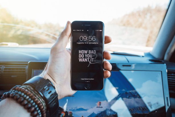 Mão segurando um celular dentro de um carro, representando a consulta digital de serviços de trânsito.