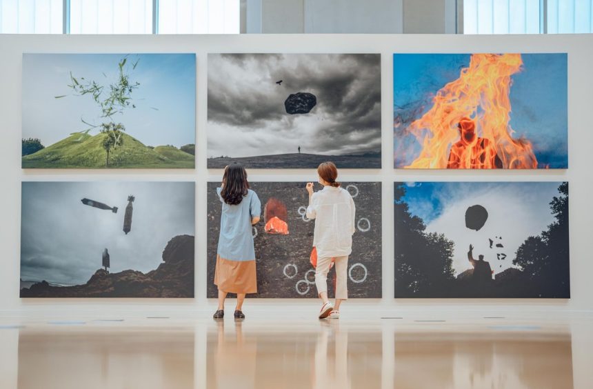 Duas pessoas observam obras de arte em uma galeria de exposição contemporânea.