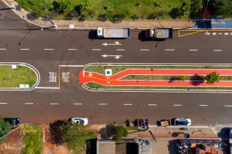 Vista aérea de uma via urbana com faixas de circulação e ciclovia demarcada.