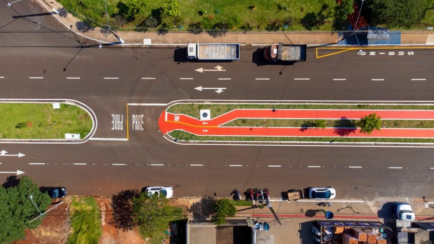 Vista aérea de uma via urbana com faixas de circulação e ciclovia demarcada.