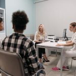 Profissionais de saúde conversam com pacientes durante uma consulta em um consultório médico.