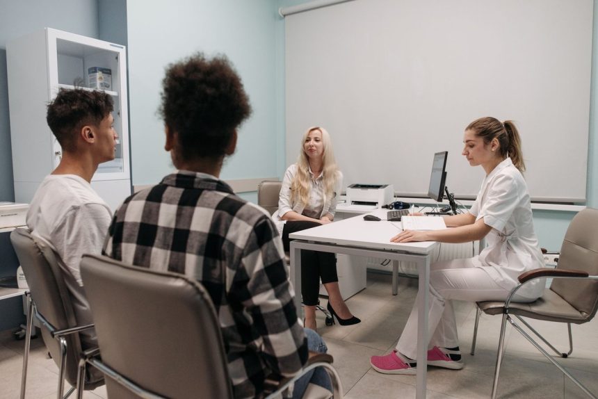 Profissionais de saúde conversam com pacientes durante uma consulta em um consultório médico.